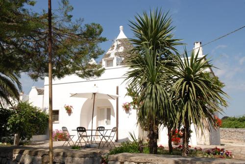 a white church with a palm tree in front of it at Trulli Dal Conte in Locorotondo