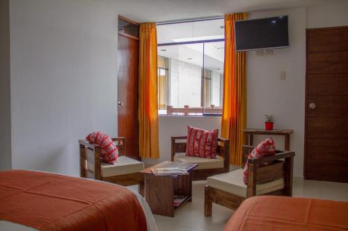 a bedroom with a bed and chairs and a television at Pandora hotel colca in Chivay