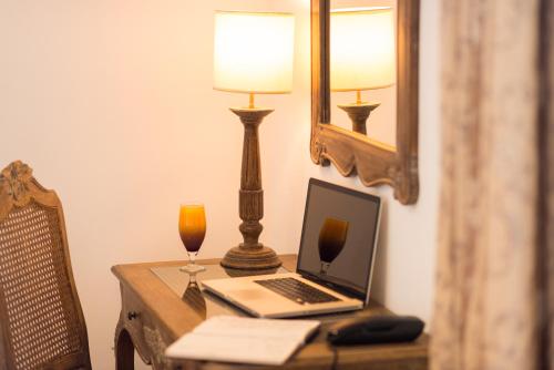 a desk with a laptop and a lamp and a drink at La Résidence in Dakar