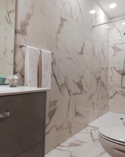 a bathroom with a toilet and a marble wall at Hotel Peninsular in Caldelas