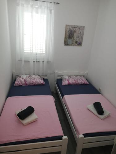 two beds in a room with pink and purple sheets at Apartment Vesna in Novalja