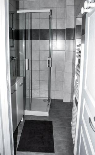 une douche avec une porte vitrée dans une salle de bain dans l'établissement Maison gîte à Vire Normandie (Les Vaux de Vire), à Vire