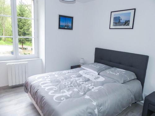 Cama en habitación blanca con ventana grande en Maison gîte à Vire Normandie (Les Vaux de Vire), en Vire