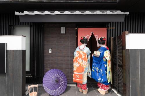 two women in kimonos standing outside a building with an umbrella at Stay SAKURA Kyoto Kiyomizu Gojo in Kyoto