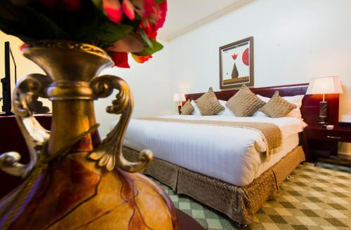 a hotel room with a bed and a vase of flowers at The Manor Hotel in Kigali