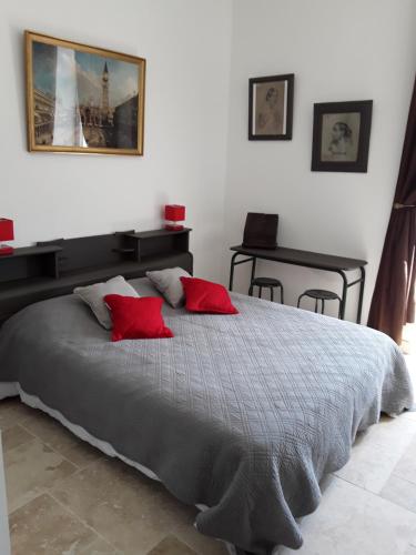 ein Schlafzimmer mit einem großen Bett mit roten Kissen in der Unterkunft LE MOULIN A VENT in Bertric-Burée