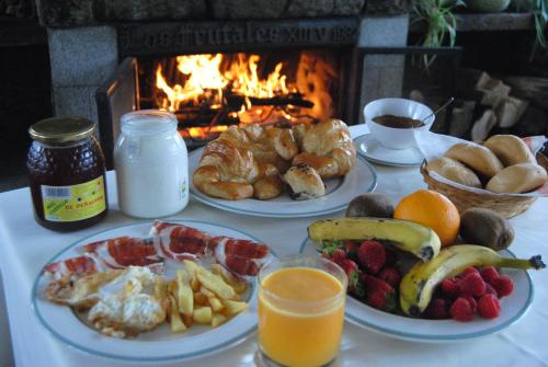 a table with plates of breakfast food and a fireplace at Hotel Rural Los Frutales in Cercedilla