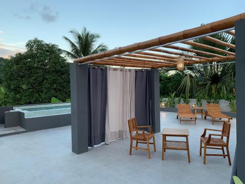 a pergola with chairs and tables on a patio at Dalai Home in Kuta Lombok