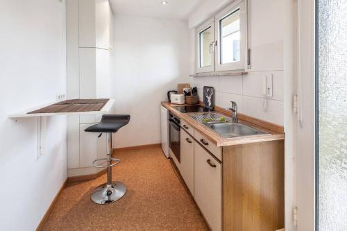 una pequeña cocina con fregadero y taburete en GL Single Town Apartment en Wiesbaden