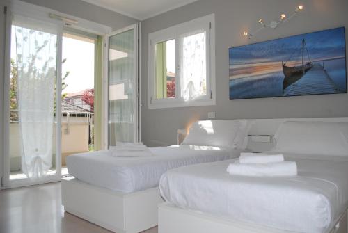 two white beds in a white room with windows at Bnbook - Metropolitan Expo Flat 4 in Rho