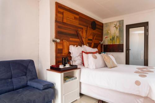 a bedroom with a bed and a blue chair at SelaMod Village Guest House in Tshaneng