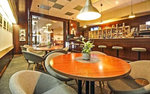 um restaurante com mesas e cadeiras e um bar em Hotel Adamantino em Luhačovice