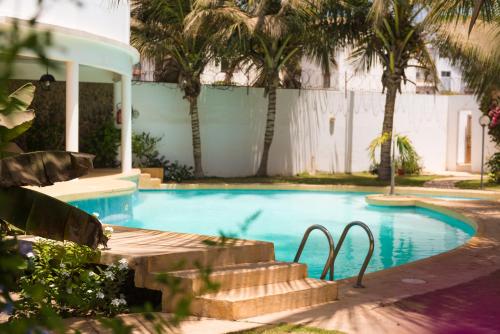 a swimming pool with palm trees and a house at La Résidence in Dakar