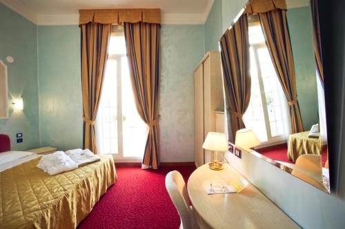 Cette chambre comprend un lit, une table et un miroir. dans l'établissement Grand Hotel Cesenatico, à Cesenatico