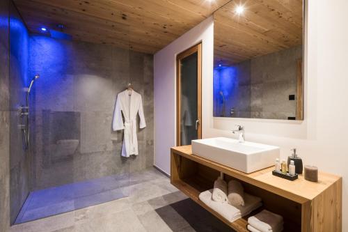 a bathroom with a sink and a shower at Les Dolomites Mountain Lodges in San Martino in Badia