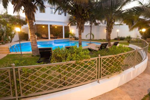 a resort pool with palm trees and chairs at La Résidence in Dakar
