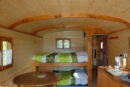 a room with a bed and a table in a cabin at La Ferme du Marais Poitevin - Roulotte in Benet