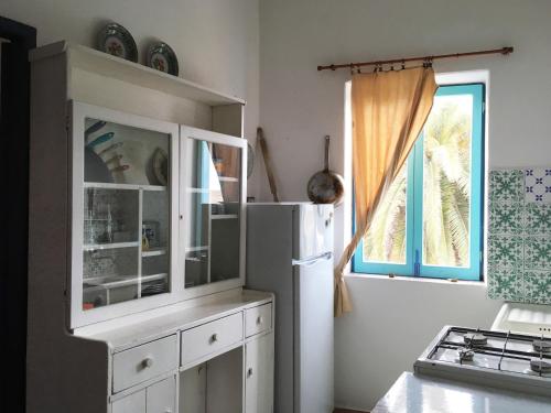 a kitchen with a white refrigerator and a window at Le Case del Capitano in Stromboli