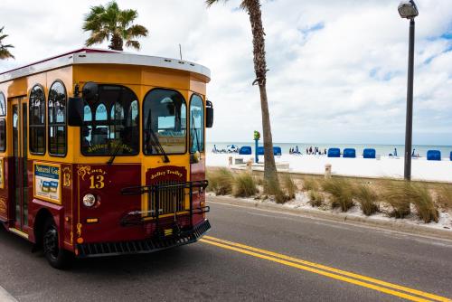 a bus driving down a road next to the beach at NEW 2bed2bath condo - CLEARWATER BEACH - FREE Wi-Fi and Parking in Clearwater