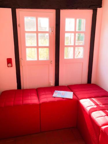 a red couch in a room with two windows at Hexenhäuschen Dreieichenhain in Dreieich