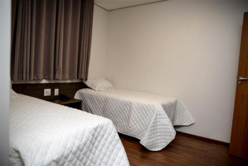 a hotel room with two beds and a table at Grand Café Hotel in Manhuaçu