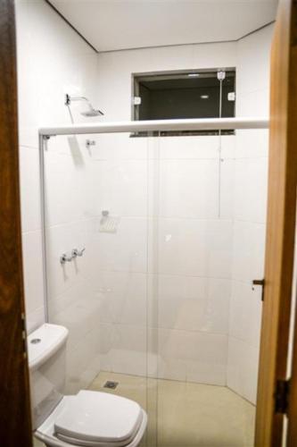 a bathroom with a toilet and a glass shower at Grand Café Hotel in Manhuaçu
