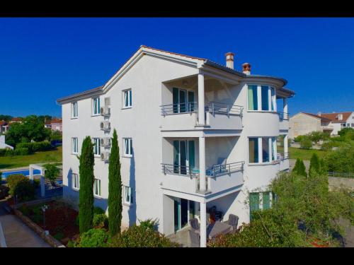 a large white building with trees in front of it at Apartments Kovacic in Malinska