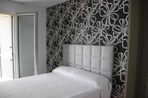 1 dormitorio con cama blanca y papel pintado con motivos florales en APARTAMENTO BRUSELAS, en Salou