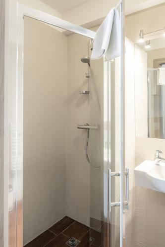 a shower with a glass door next to a sink at 7 Koron - Exclusive Apartments in Kraków