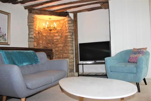 a living room with two chairs and a tv at Historic Grade II Listed Homely Cottage in Stamford