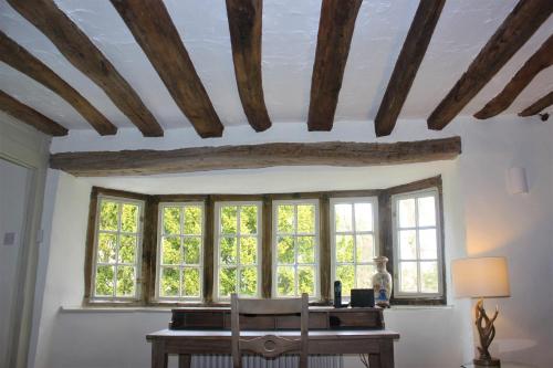 a room with a table and windows with a desk at Historic Grade II Listed Homely Cottage in Stamford