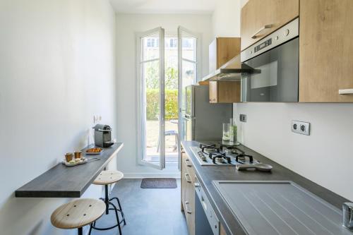 - une cuisine avec une cuisinière et un comptoir avec des tabourets dans l'établissement Nice Apartment Garden - 5 min DISNEYLAND Paris - Val d'Europe Center, à Chessy