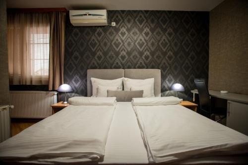 a bedroom with a large bed with white sheets at Garni Hotel Radović in Kragujevac