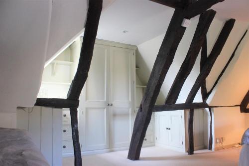 a room with white cabinets and wooden beams at Historic Grade II Listed Homely Cottage in Stamford
