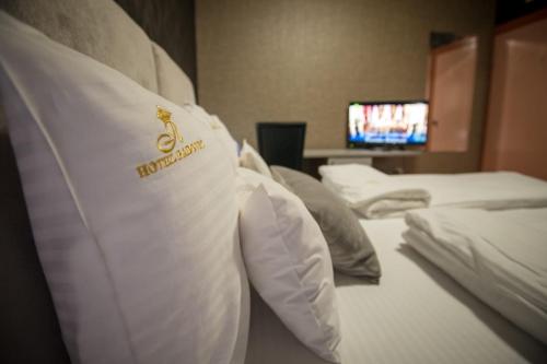 a hotel room with three beds and a tv at Garni Hotel Radović in Kragujevac