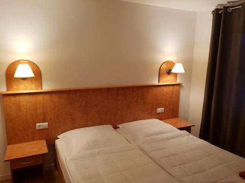 a bedroom with a bed and two lights on the wall at Hotel Krone UG in Deißlingen