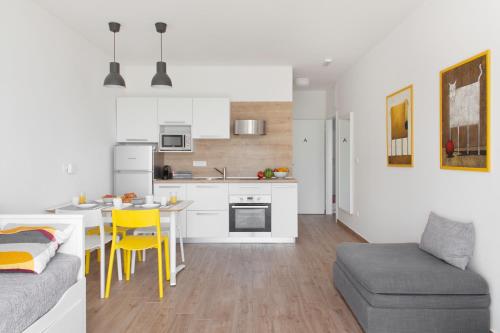 a kitchen and living room with a table and yellow chairs at Apartments Coast 27 in Podgora