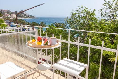 a table with a tray of fruit on a balcony at Apartments Coast 27 in Podgora