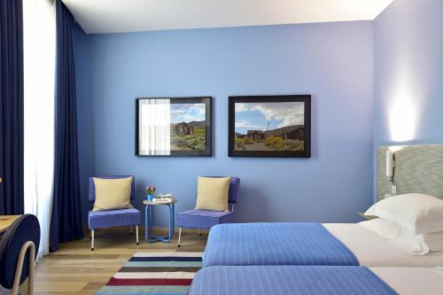 a blue bedroom with a bed and two chairs at The Editory House Ribeira Porto Hotel in Porto