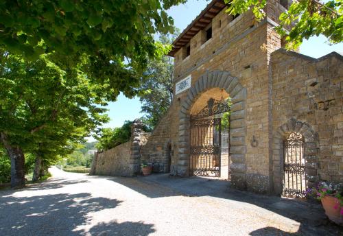 a large stone building with a clock on the side of it at Castello di Cafaggio Borgo in Impruneta
