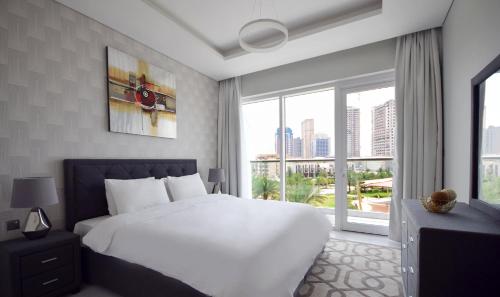 a bedroom with a white bed and a large window at KeyHost - Regent Court JVC - K390 in Dubai