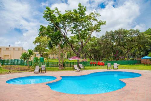 een zwembad met stoelen, tafels en bomen bij Sunbird Mzuzu in Katoto