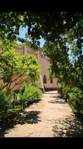 a walkway in front of a building with trees at Nubian Holiday House Aswan in Aswan