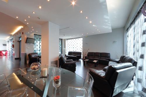 a living room with a glass table and leather furniture at Hotel Relax Roma Nord in Fiano Romano