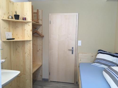 a room with a bed and a wooden door at Pensiun Lischana in Sent