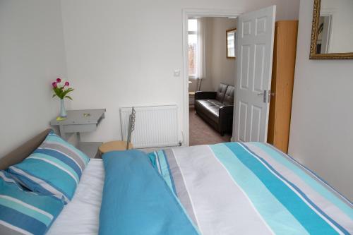 Schlafzimmer mit einem Bett mit blauer und weißer Bettwäsche in der Unterkunft Alphalink Apartment in Middlesbrough