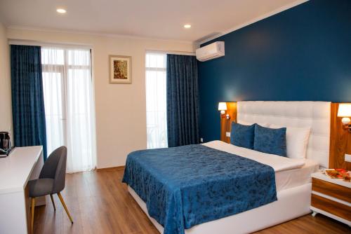 a hotel room with a bed and a blue wall at Aqua Batumi Hotel & Apartments in Batumi