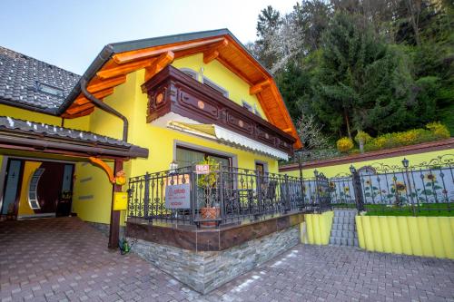 une maison jaune avec un balcon et une clôture dans l'établissement Rooms Močilnik, à Begunje na Gorenjskem