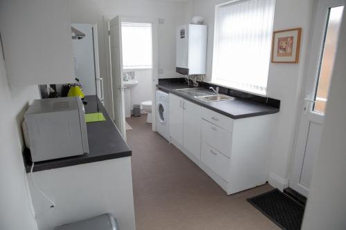 a white kitchen with a sink and a stove at Alphalink Apartment in Middlesbrough