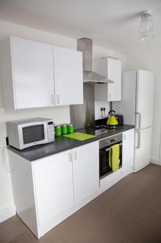 a kitchen with white cabinets and a microwave at Alphalink Apartment in Middlesbrough